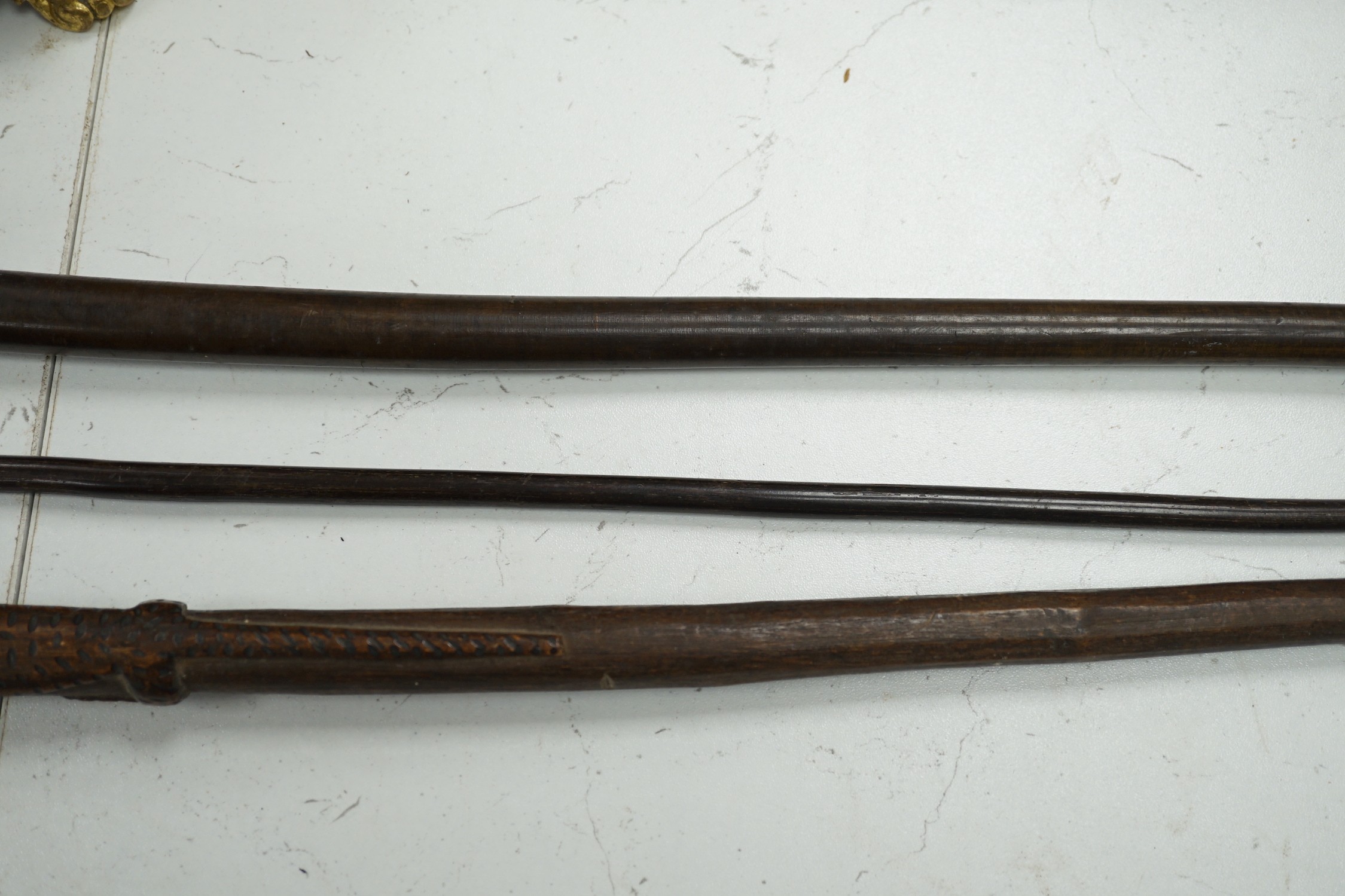 A bull's pizzle walking stick and two other carved wood sticks, largest 93cm